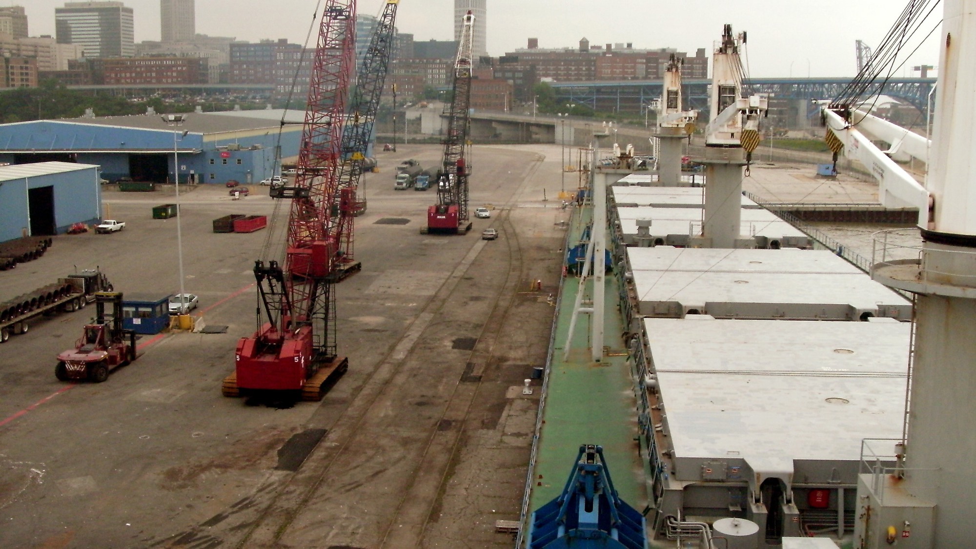 A bulk carrier alongside, hatch covers open and quayside cranes working the berth
